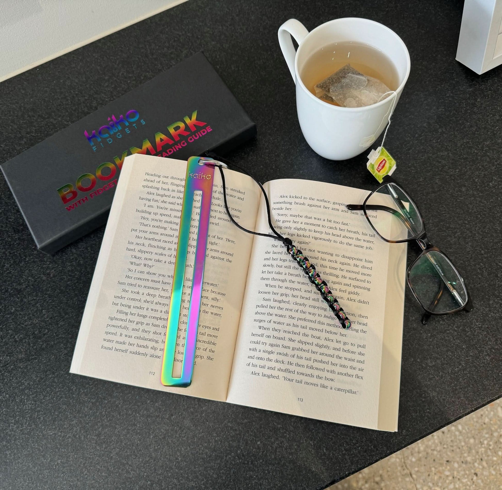 Kaiko Fidgets metal bookmark in oil slick finish with reading guide pane and fidget hook for sensory focus aid